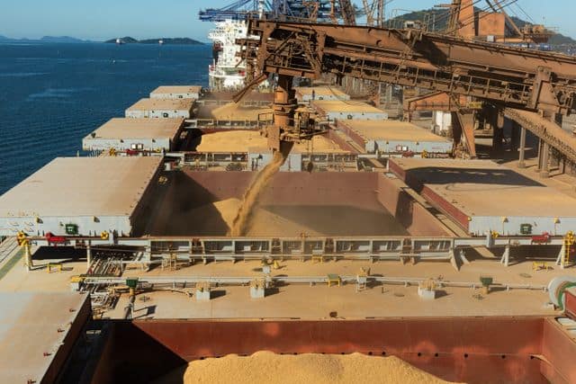Black Sea Wheat Market Report — September 2026 Aerial view of a cargo ship loading grain at a bustling industrial port by the sea.